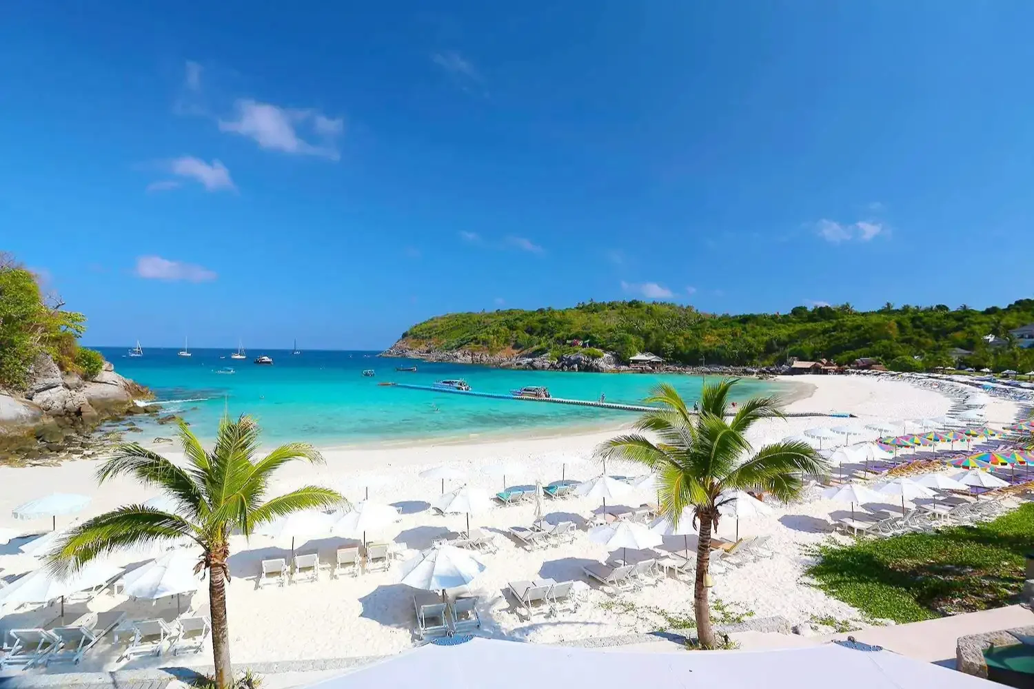 Panoramic view over the bay at Racha Yai Island featuring turquoise waters, anchored boats, and lush coastal scenery