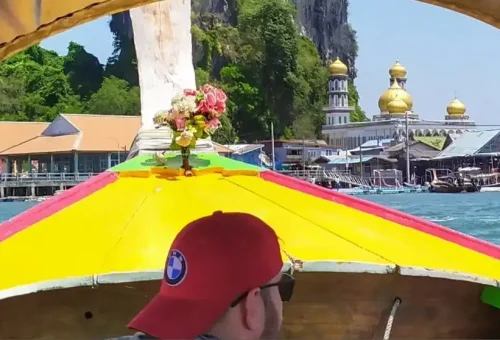 Traditional longtail boat approaching Koh Panyee, a floating village in Phang Nga Bay surrounded by limestone cliffs