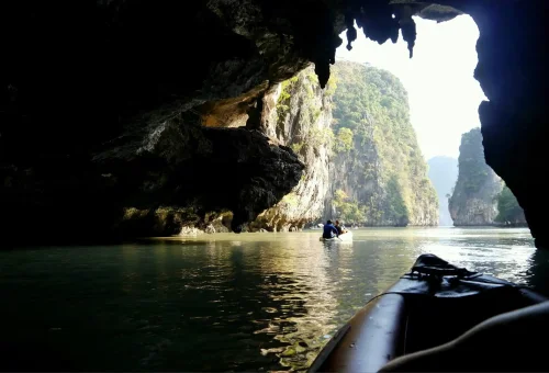 Tourist canoeing through crystal-clear waters and limestone caves at Hong Island in Phang Nga Bay