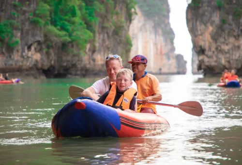 Travelers paddling a canoe through sea caves and emerald lagoons in Phang Nga Bay during a guided adventure tour