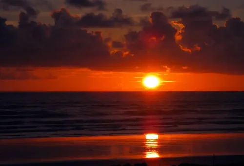 Early morning sun rising over calm waters and limestone karsts in Phang Nga Bay, Thailand