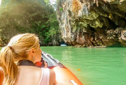 Tourist canoeing through scenic sea caves and clear waters at Hong Island in Phang Nga Bay, Thailand