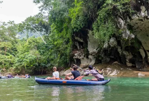 Tourist canoeing on the Sok River in Khao Sok National Park – rainforest reflections and limestone cliffs in the background