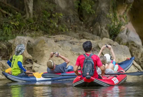 Canoeing through the calm, emerald-green waters of the Sok River surrounded by limestone cliffs and rainforest in Khao Sok National Park