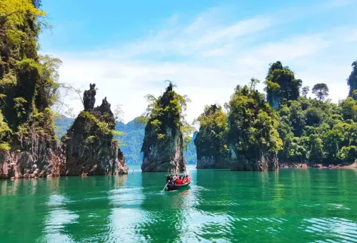 Scenic lagoon with emerald-green water and limestone cliffs at Cheow Lan Lake in Khao Sok National Park