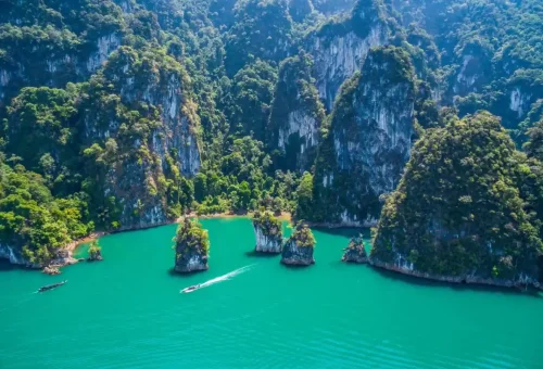 Aerial view of a stunning turquoise lagoon surrounded by limestone mountains at Cheow Lan Lake in Khao Sok National Park