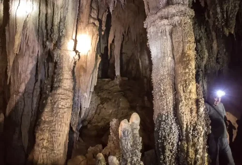 Traveler exploring a limestone cave near Cheow Lan Lake in Khao Sok National Park on a guided tour with Phuket Travel Store