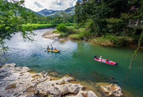 Canoeing on the Sok River at Khao Sok National Park with Phuket Travel Store, passing limestone cliffs and lush rainforest scenery.