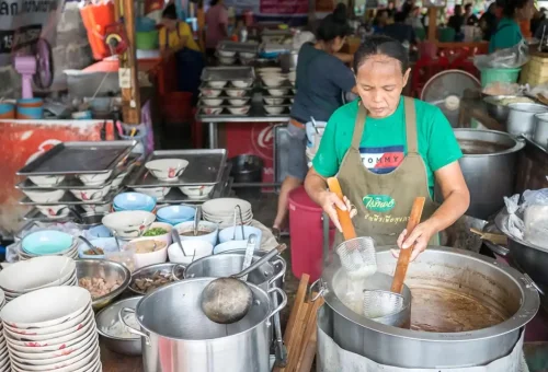 Visitor enjoying boat noodles while exploring Wat Mahathat and sampling street food