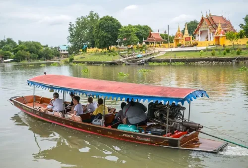 Visitor enjoying fried bananas while exploring Wat Phu Khao Thong and cruising along the Chao Phraya River