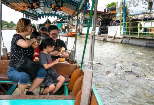 Visitor enjoying kanom jeen while exploring Wat Phra Ram and taking photos of ancient Buddha heads