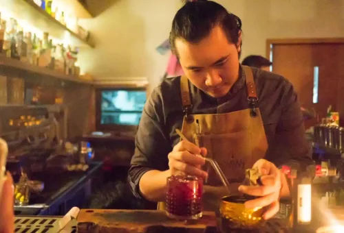 Couple clinking glasses at a rooftop bar during the Bangkok bar crawl tour