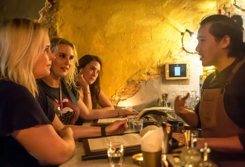 Colorful tuk tuk parked outside a Bangkok bar with guests ready to hop in