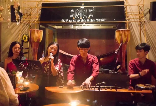 Group of friends enjoying cocktails at a rooftop bar in Bangkok with city skyline