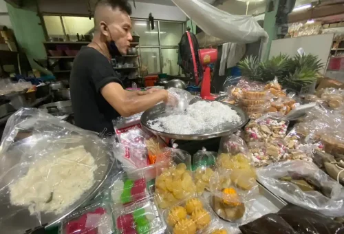 Guest enjoying fried chicken with sticky rice at Wang Lang Market during Bangkok Midnight Food Tour by Tuk Tuk with Phuket Travel Store