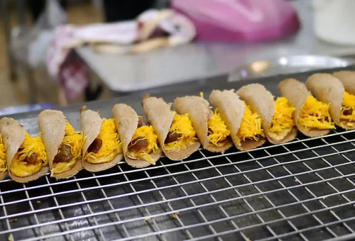 Guest enjoying crispy pork belly at Saphan Han bridge during Bangkok Midnight Food Tour by Tuk Tuk with Phuket Travel Store
