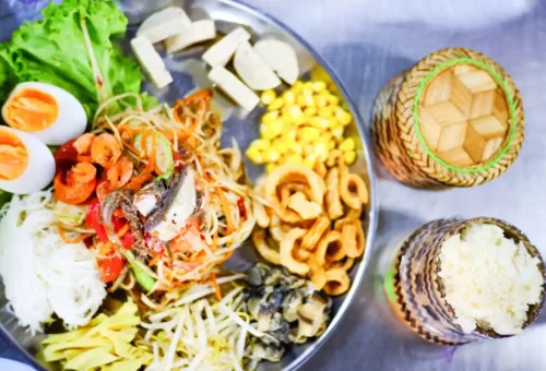 Colorful Thai papaya salad platter with sticky rice and local toppings