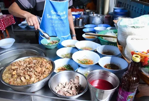 Authentic Bangkok street food vendor preparing pork noodles