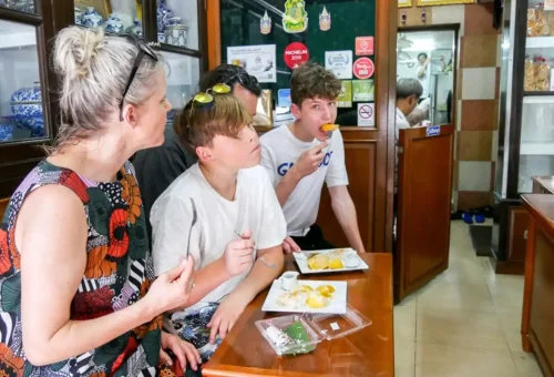 Family eating mango sticky rice inside a traditional Thai eatery