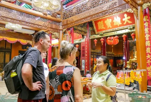 Tour guide explaining temple history to tourists inside ornate shrine