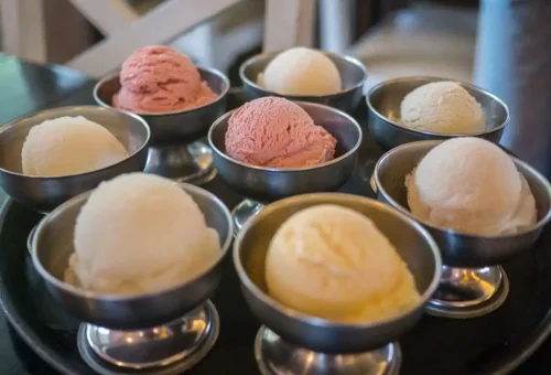 Scoops of coconut and fruit ice cream in metal dessert bowls