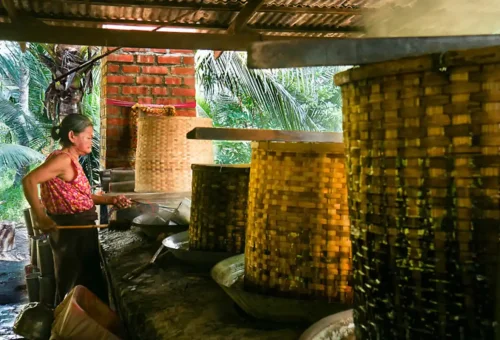 Thai woman boiling palm sugar at a traditional coconut farm