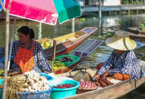 Women selling produce from boats at a traditional Bangkok floating market