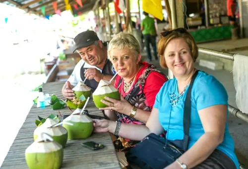 Tourists enjoying fresh coconut juice at a floating market in Bangkok