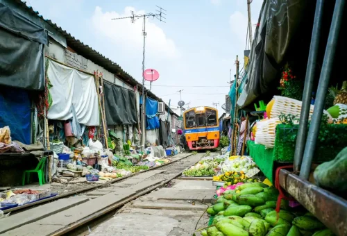 Local train approaching through Maeklong Railway Market in Bangkok