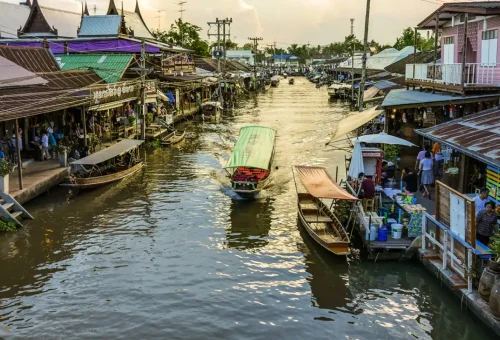 Boat navigating through a canal lined with riverside shops at dusk