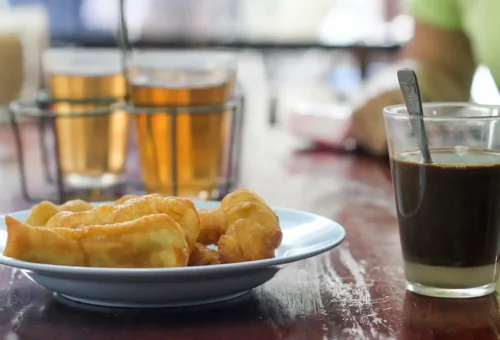 Traditional Thai breakfast of deep-fried Chinese donuts served with black coffee and tea