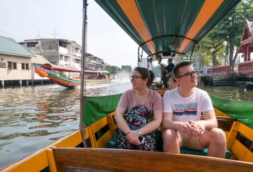 Tourists on a colorful longtail boat enjoying a scenic canal ride through Thonburi, Bangkok