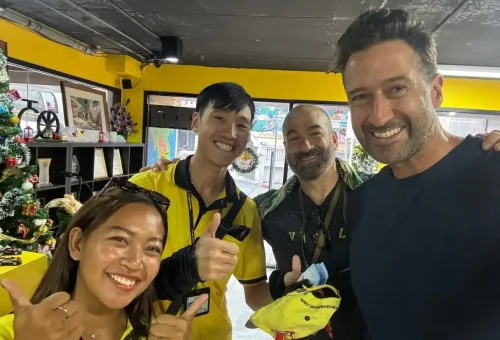 Group of travelers smiling with Co Van Kessel tour team after a Bangkok cycling tour.