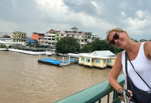 Traveler cycling through a bustling Bangkok street market past hanging dried fish.