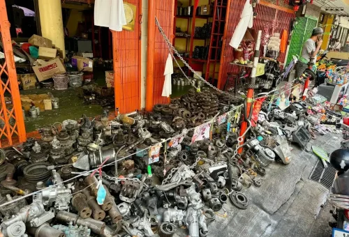 Tourist cycling past a lively Bangkok street food stall with hanging fish and local vendors during a full-day bike tour.