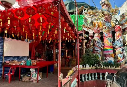 Colorful Chinese temple with red lanterns and dragon pillars spotted on a Bangkok bicycle tour route, showcasing local culture and hidden gems.