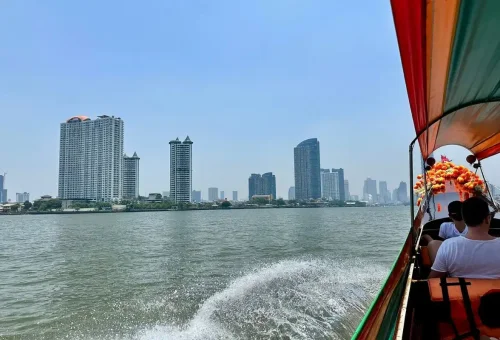 Longtail boat on Chao Phraya River with Bangkok skyline