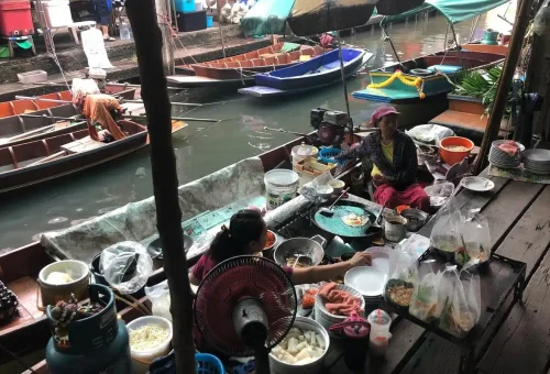 Thai women cooking food from a floating market stall
