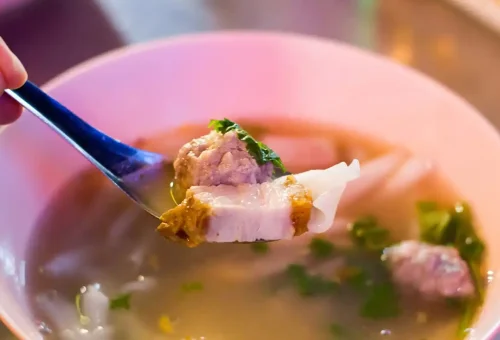 Spoonful of pork and rice noodles in clear broth from Bangkok stall