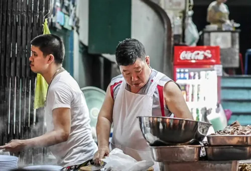 Local vendor preparing ingredients in a traditional noodle shop