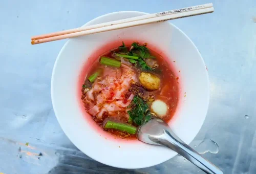 Bowl of Yen Ta Fo (pink noodle soup) with greens and fish balls