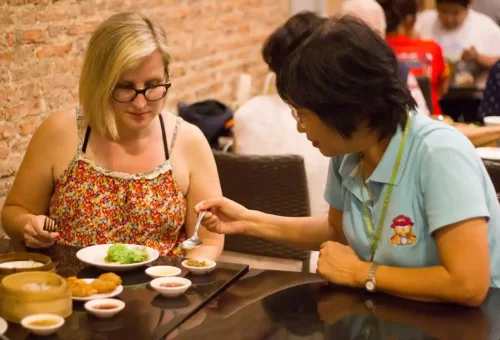 Tour guide explaining dishes to guest inside a local Chinatown restaurant