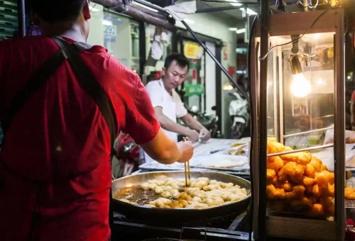 Street vendor frying Thai dough sticks at Yaowarat night market