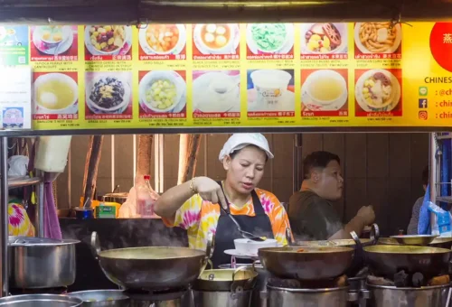 Street food vendor serving hot desserts under a colorful menu board