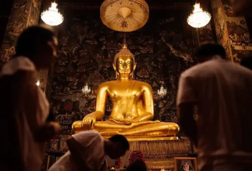 Worshippers bow before a golden Buddha statue inside a hidden temple in Bangkok's old quarter.
