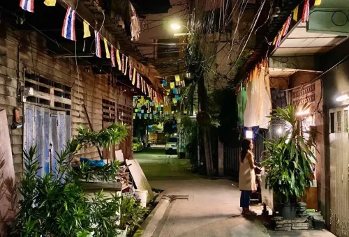 Traditional wooden homes and festive flags create a nostalgic scene in Bangkok’s historic district.