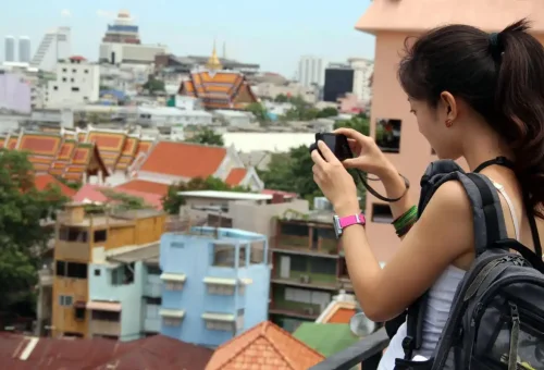 Tourist capturing Bangkok’s skyline with camera from rooftop