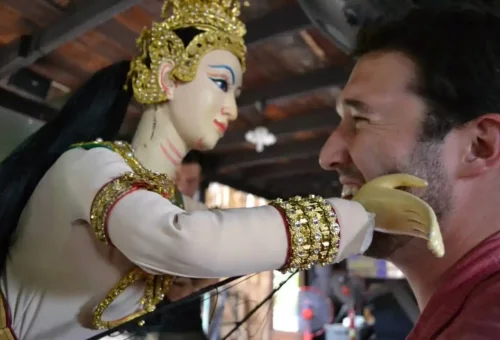 Traveler interacting with traditional Thai puppet in Bangkok