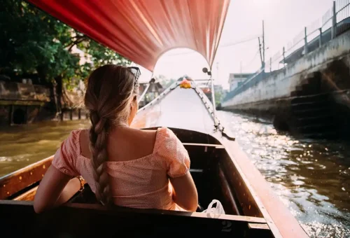 Woman riding a longtail boat through Bangkok’s canals at sunset