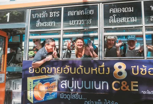 Happy tourists waving from a local Bangkok bus